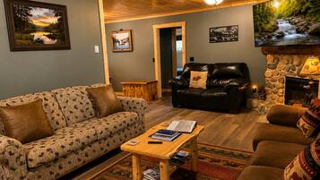 A cozy living room with a sofa, a coffee table, a fireplace, and a television.