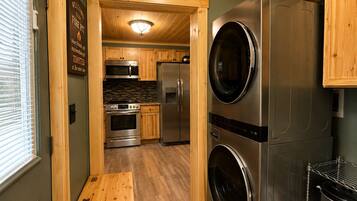 A compact kitchen with stainless steel appliances, wooden cabinetry, and a built-in oven.
