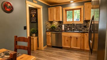 A kitchen with wooden cabinets, a stainless steel refrigerator, and a stone backsplash.