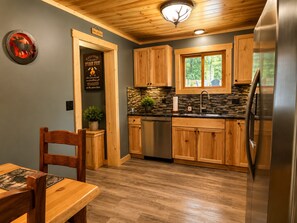 Eine Küche mit Holzschränken, einem Edelstahlkühlschrank und einer Rückwand aus Stein.