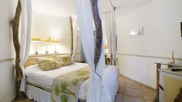 A bedroom with a canopy bed, bedside lamps, a nightstand, and a dresser.