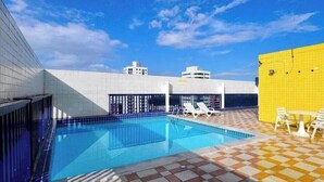 Une piscine avec un sol à carreaux, des chaises longues et un ciel dégagé.