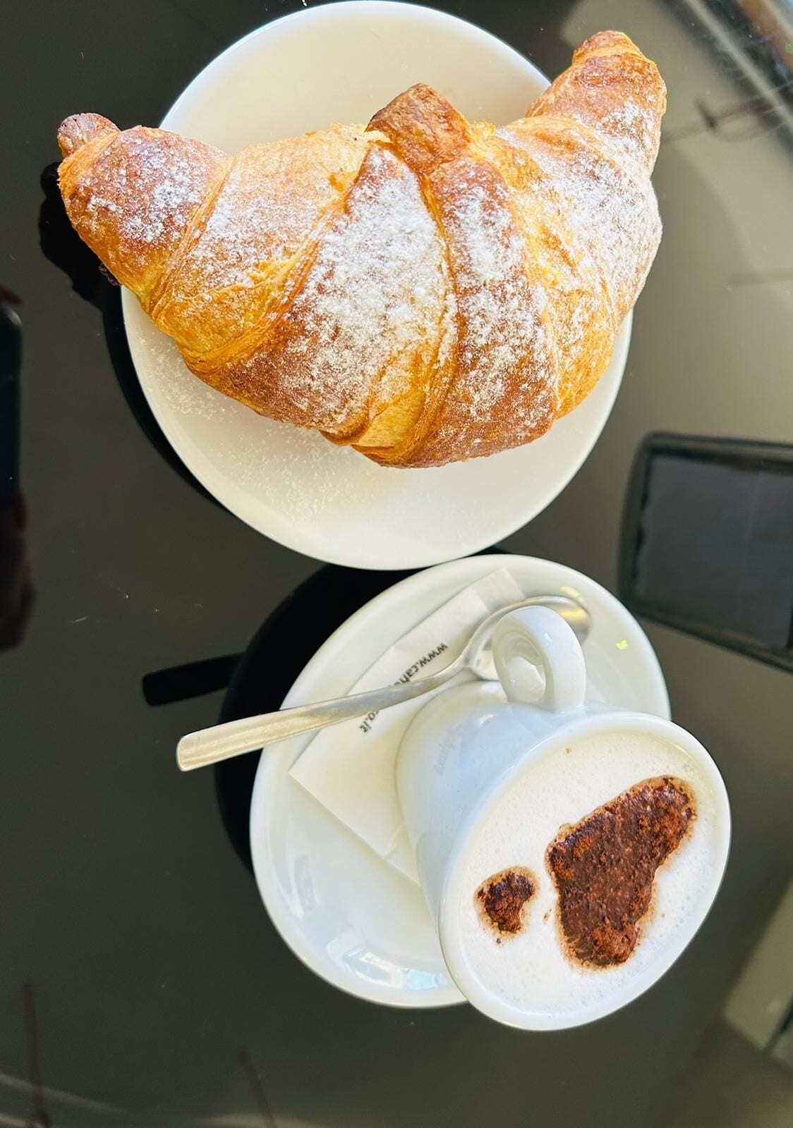 A croissant and a cup of coffee on a table.
