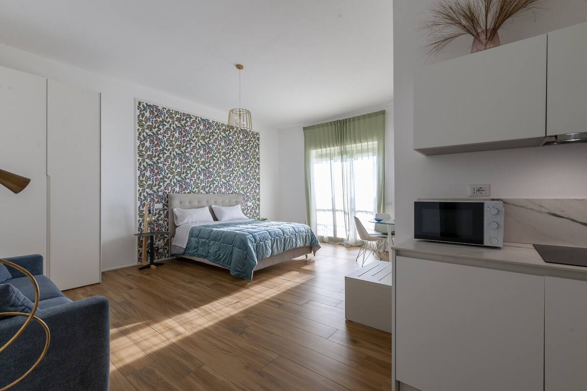 Un dormitorio moderno con cama, escritorio y microondas.