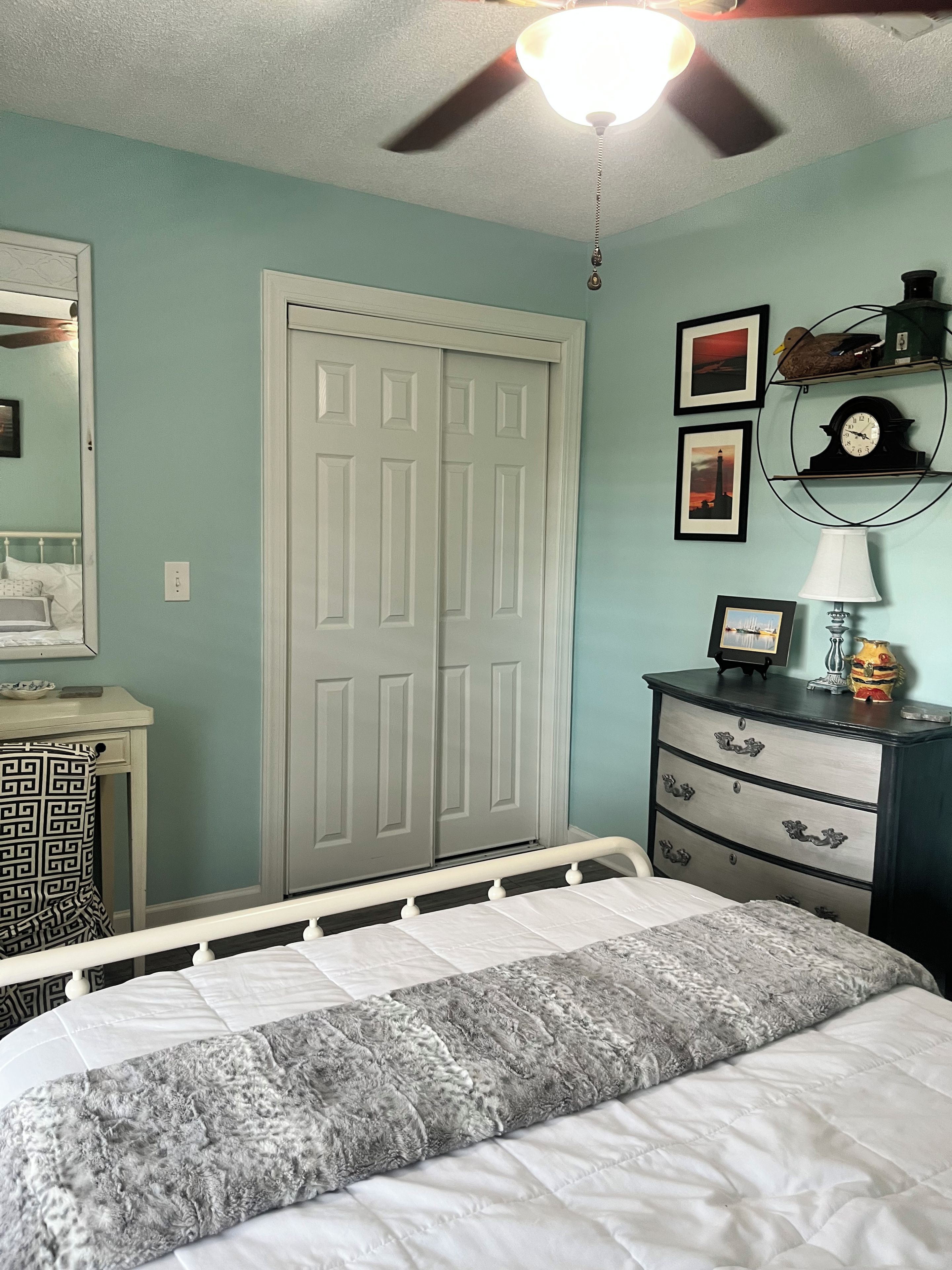 A bedroom with a bed, a dresser, a wardrobe, and a ceiling fan.