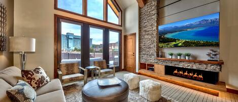 Una sala de estar moderna con chimenea, ventanas amplias y televisor de pantalla plana.