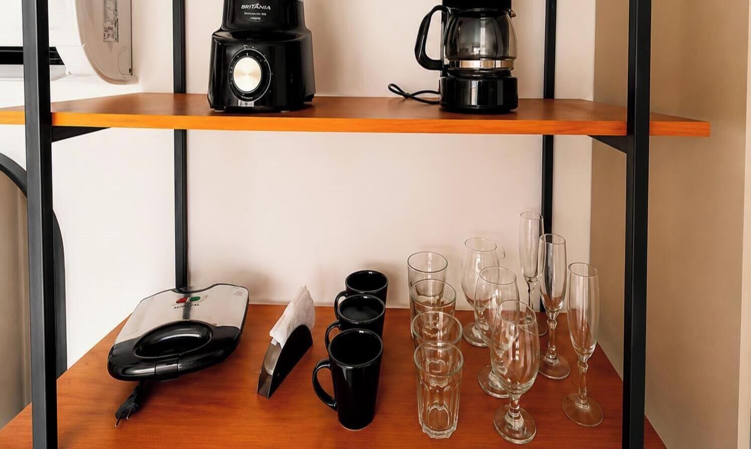 Una encimera de cocina con una cafetera, una balanza, tazas y copas de vino.