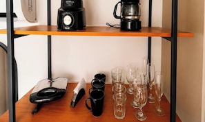 A kitchen counter with a coffee maker, a scale, mugs, and wine glasses. - Breeze Residence (João Pessoa)