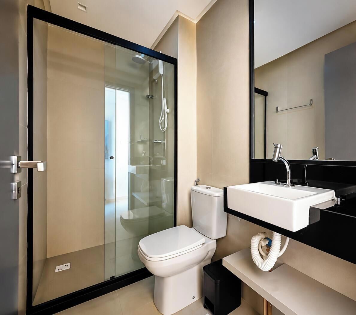 A modern bathroom with a glass-enclosed shower, a white toilet, and a black countertop with a white sink.