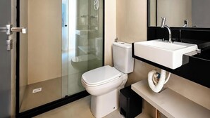 Et moderne badeværelse med et brusebadeværelse med glasvægge, et hvidt toilet og en sort bordplade med en hvid vask.