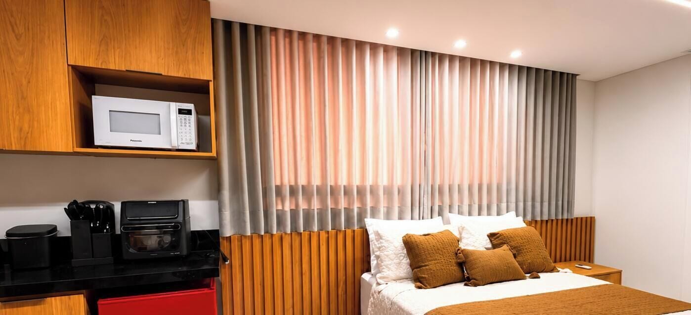 Una habitación de hotel con una cama, microondas, cafetera y un armario rojo.