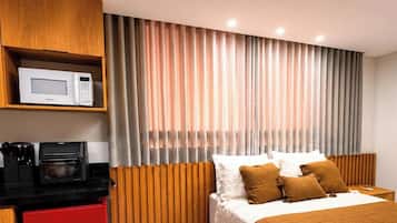 Una habitación de hotel con una cama, microondas, cafetera y un armario rojo.