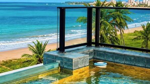Udebane infinity pool med udsigt over strand og hav.