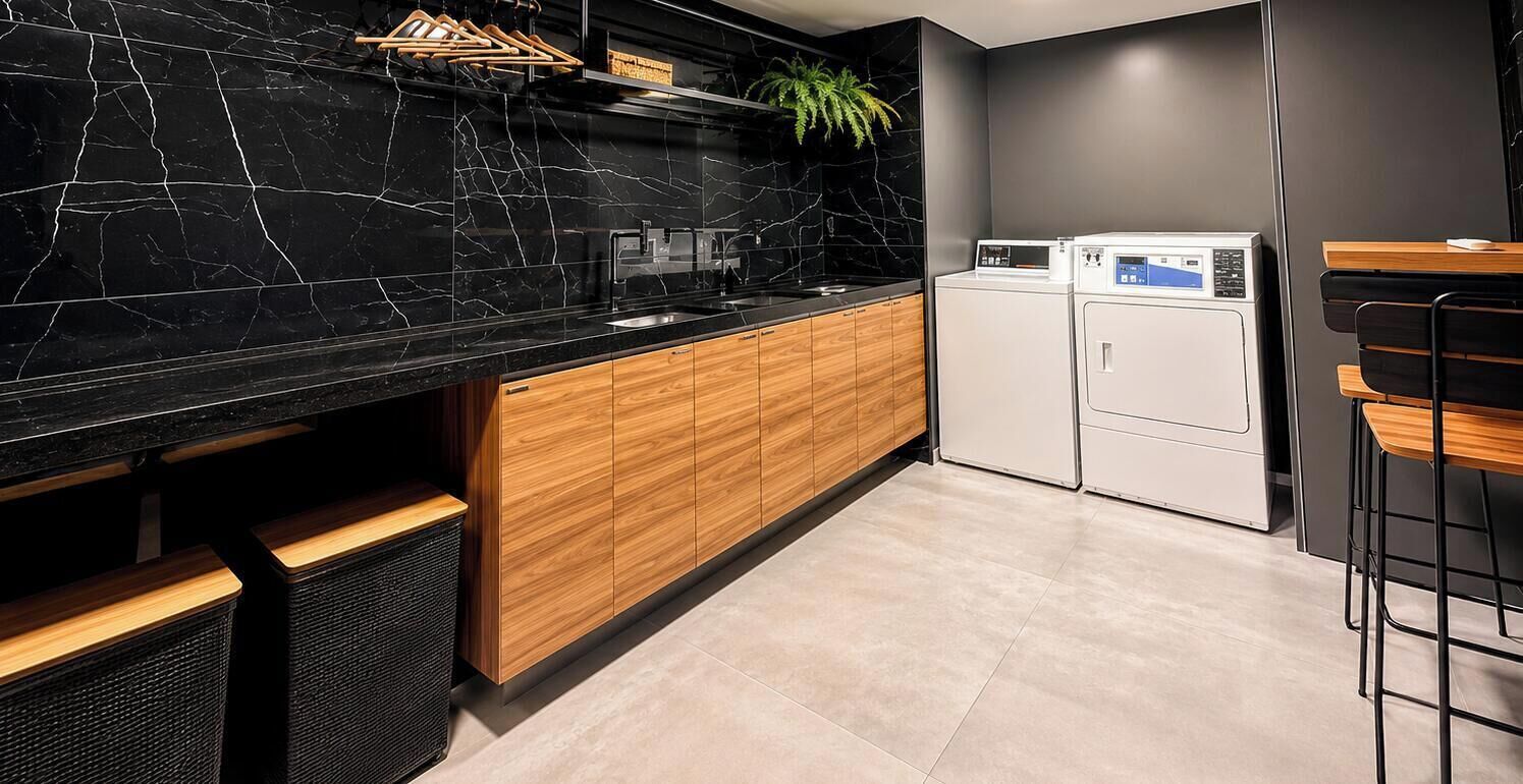 Una cocina moderna con encimera de mármol negro, armarios de madera y lavadora integrada.