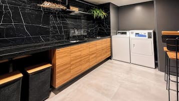 Una cocina moderna con encimera de mármol negro, armarios de madera y lavadora integrada.