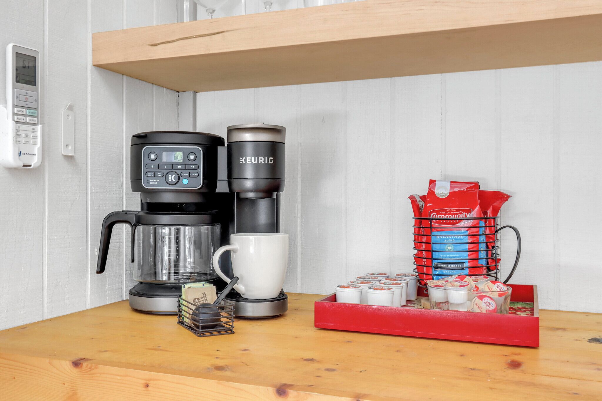 Una cafetera, una taza de café y un paquete de café sobre una mesa de madera.