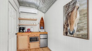 Eine kompakte Küche mit Holzausbau, inklusive Backofen, Kühlschrank und Kaffeemaschine.