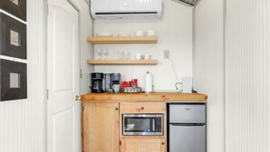Una cocina compacta con microondas integrado, refrigerador, armarios de madera y cafetera.