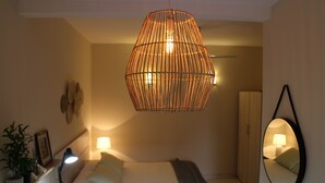A bedroom with a bed, bedside table, lamp, hanging light fixture, wardrobe, and a mirror on the wall. - De la Mora Hostal (Fernando De La Mora)