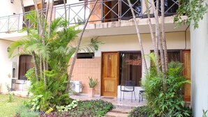 A two-story building with a balcony, a wooden door, and a small garden area with plants and a pathway. - De la Mora Hostal (Fernando De La Mora)
