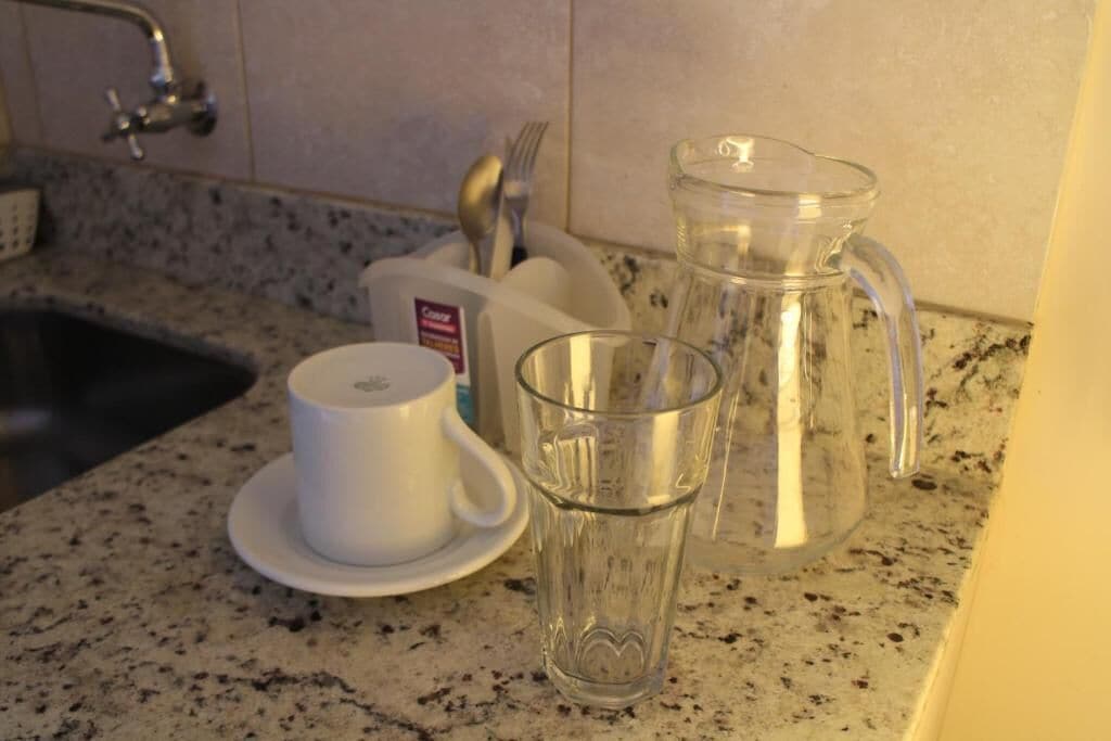 Una encimera de cocina con una taza de café, un vaso y una jarra.