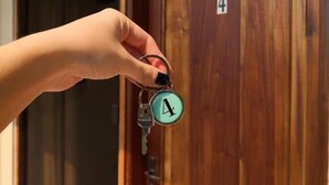 A hand holding a key with a number 4 on it, in front of a wooden door. - De la Mora Hostal (Fernando De La Mora)
