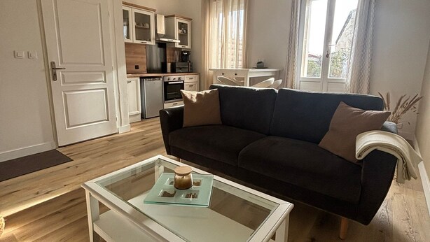 A compact living space with a kitchenette, a sofa, and a coffee table. - Duplex Cosy à Floirac - Your Haven of Light and Comfort (floirac)