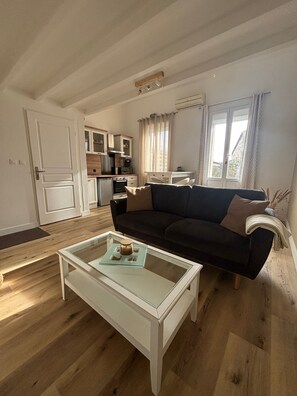 Ein gemütlicher, kleiner Wohnraum mit Küchenzeile, einer Couch und einem Couchtisch.