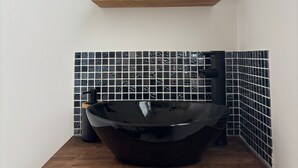 A bathroom with a wooden vanity, a black vessel sink, and a round mirror above. - Duplex Cosy à Floirac - Your Haven of Light and Comfort (floirac)