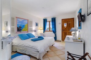 Une chambre à coucher avec un lit, une chaise, un bureau, une fenêtre avec des rideaux et une porte.