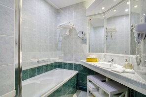Une salle de bain moderne avec une douche à parois de verre, une grande baignoire, un meuble-lavabo avec un évier et un miroir, et un banc.