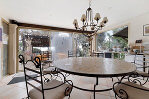 Un espace repas comprenant une table ronde, des chaises, un lustre et une vue sur l’extérieur.