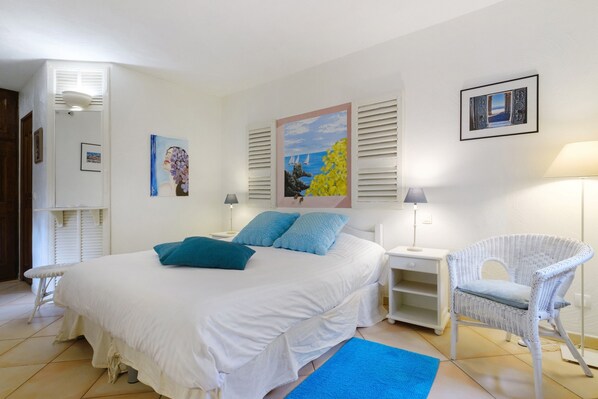 Une chambre à coucher comprenant un lit, une chaise, une table de chevet et un mur décoré d’œuvres d’art.
