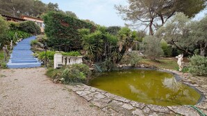 A garden with a pond, a stone pathway, and a staircase leading up a hill. - Guest Room 'Violette' with Shared Pool, Wi-Fi, and Air Conditioning (Tourrettes-sur-Loup)
