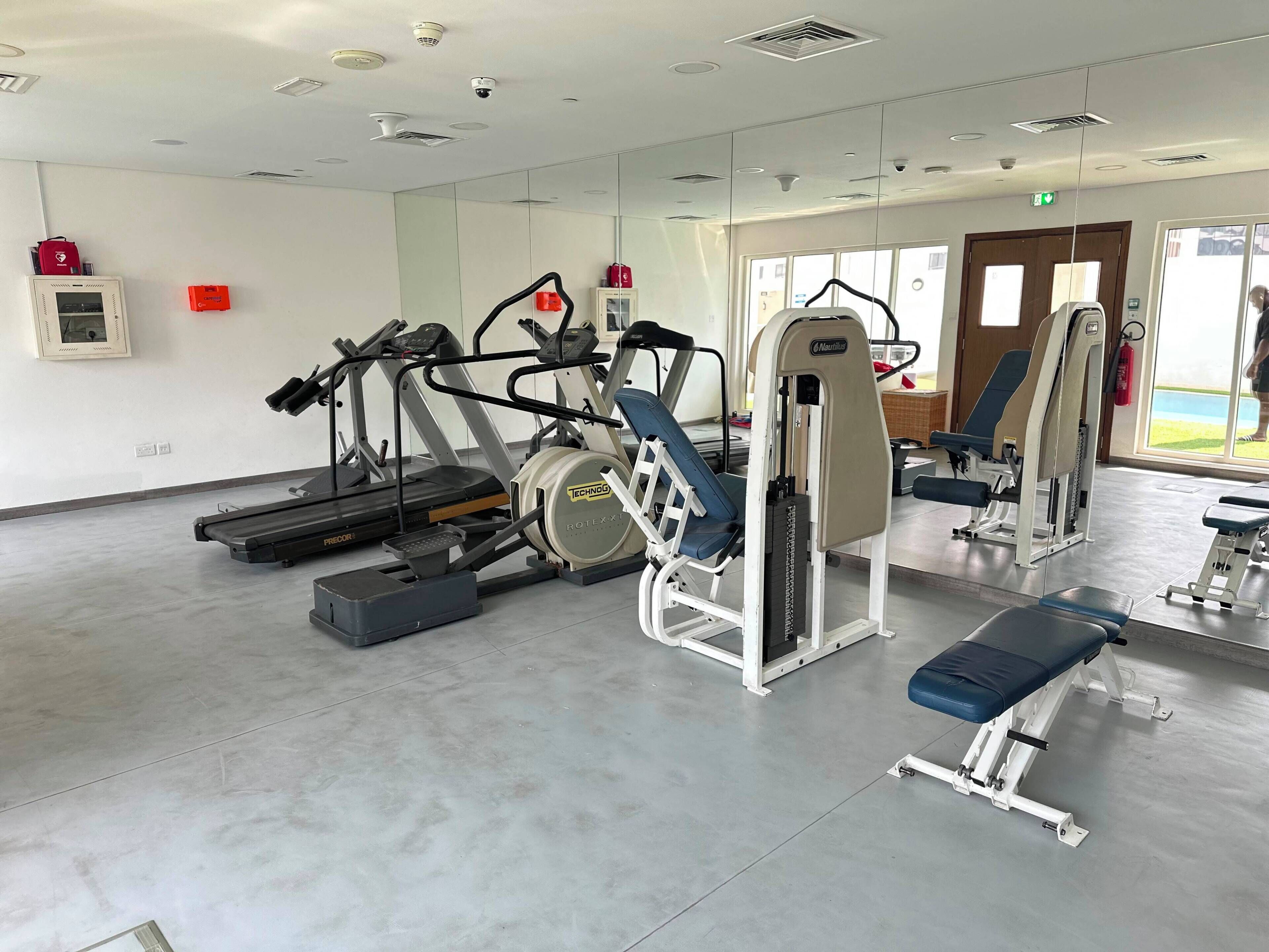 A gym with treadmills, weight machines, and benches.