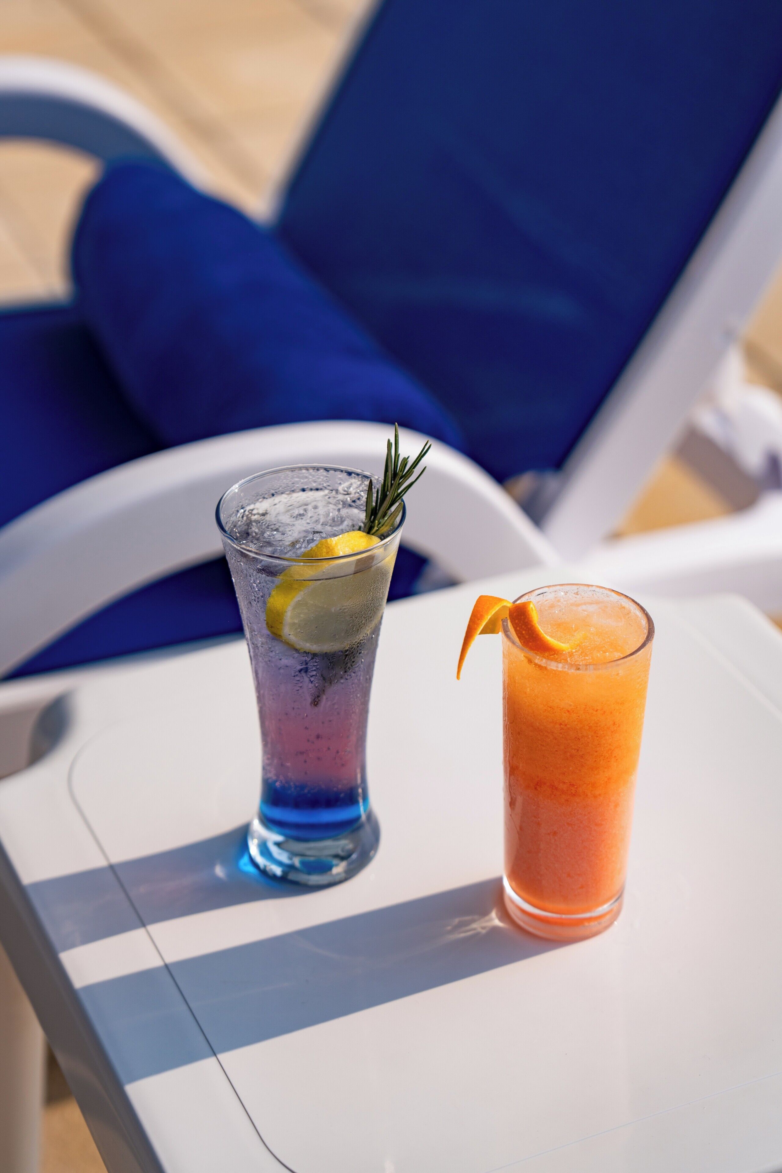 Two drinks on a table with a blue chair in the background.