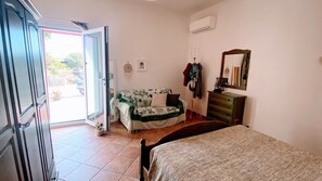 A bedroom with a bed, a dresser, a chair, and a door leading to an outdoor area. - Holiday Home 'Villa Bondormy' with Sea View, Wi-Fi and Air Conditioning (santa teresa di gallura)