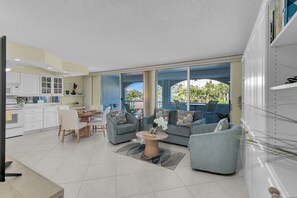 A modern living room with a sofa, coffee table, and dining area. - 1 Bed Steps to Beach Access & JW Marriott (Marco Island)