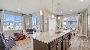 Una cocina moderna con una isla central, electrodomésticos de acero inoxidable y un amplio ventanal con vistas a la ciudad.