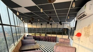 A modern interior with black and white striped flooring, cushioned seating, and pendant lighting. - SM Hotel (Ghaziabad)