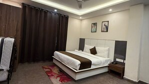 A modern bedroom with a bed, nightstand, and a ceiling fan. - SM Hotel (Ghaziabad)