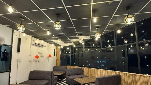 A modern interior with hexagonal ceiling lights, black and white striped flooring, and seating areas with tables. - SM Hotel (Ghaziabad)