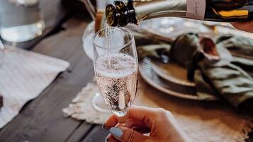 A hand holding a champagne flute filled with bubbles, with a bottle being poured into it.