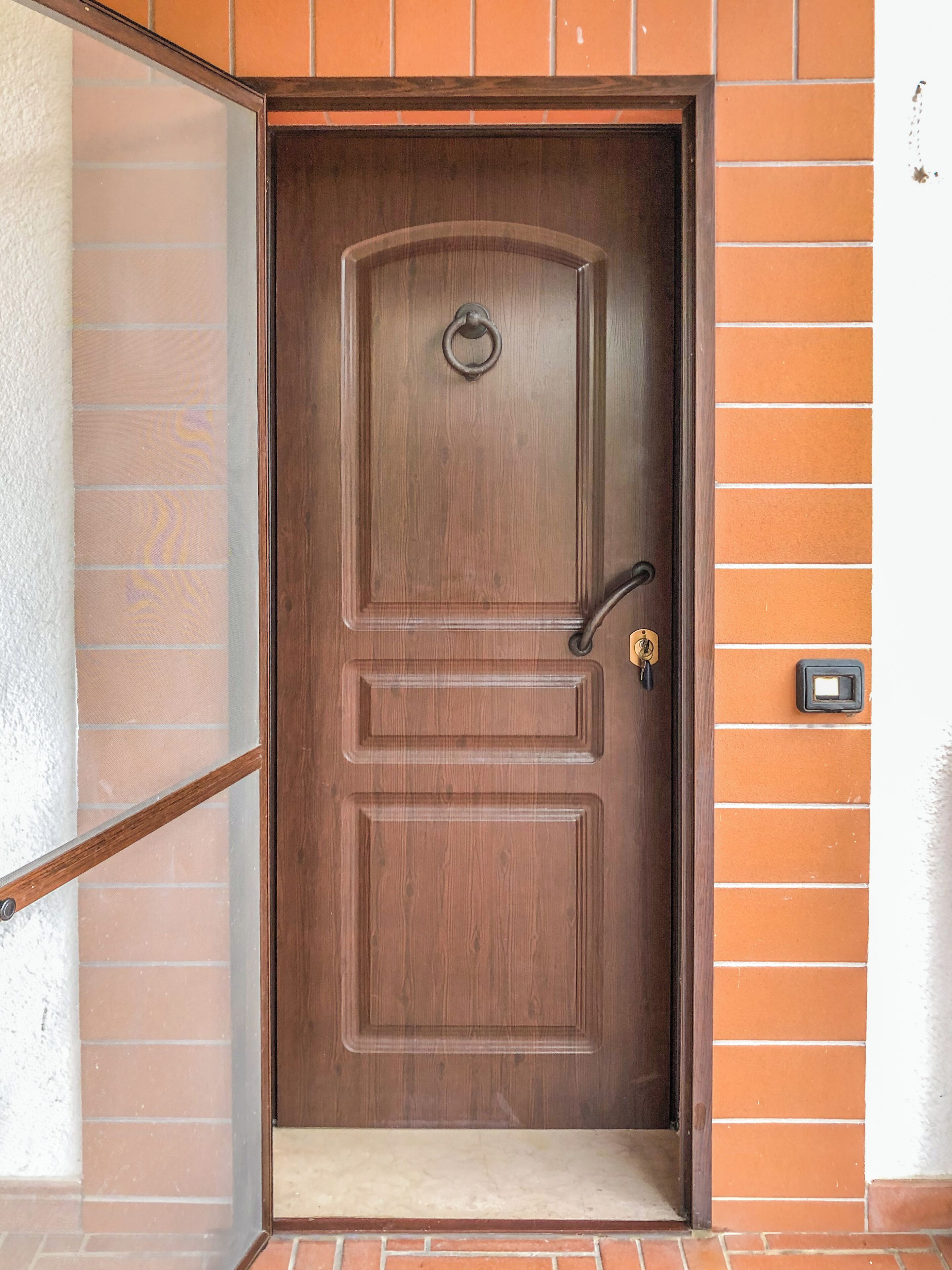 A wooden door with a handle and a keyhole, set in a brick wall.