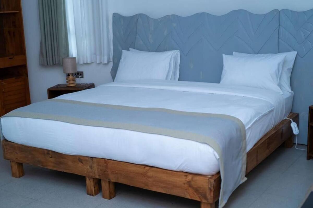 A neatly made bed with white linens and a wooden headboard.