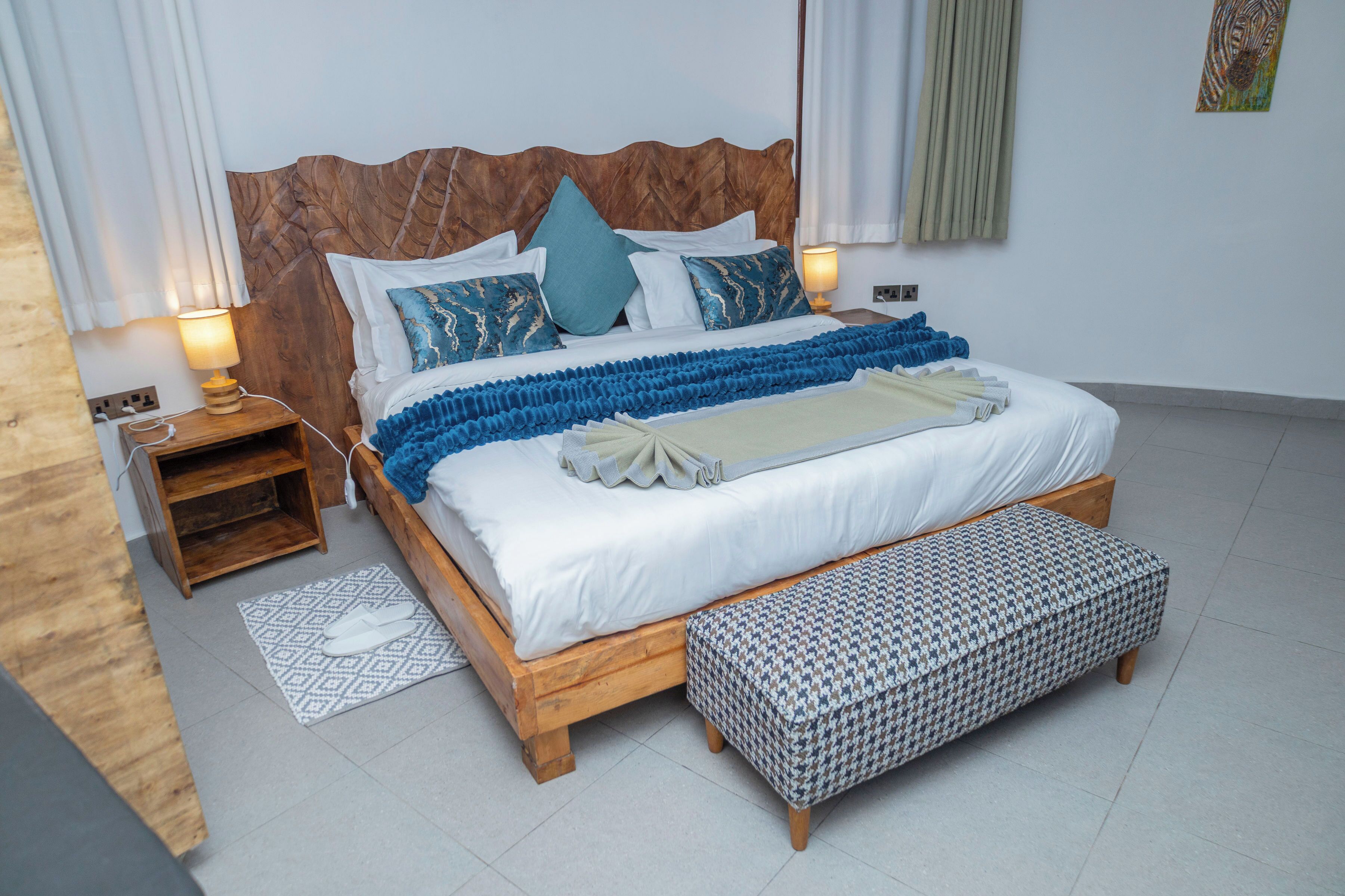 A neatly made bed with a wooden headboard, a bedside table with a lamp, and a patterned rug on the floor.