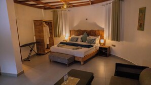 Quarto com cama de madeira, mesas de cabeceira, um banco e vista do aposento.