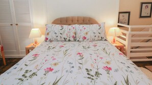 A bedroom with a floral bedspread, a tufted headboard, two bedside lamps, a white wardrobe, and a framed picture on the wall. - 6 Church Lane (Llanidloes)
