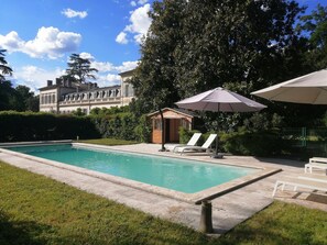 A rectangular swimming pool with a small wooden structure and lounge chairs.