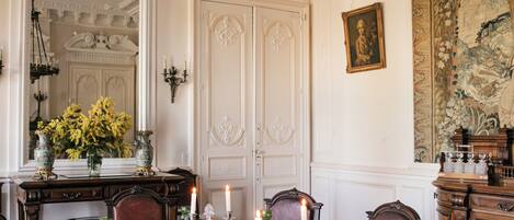 A formal dining room with a chandelier, ornate furniture, and a large tapestry on the wall.